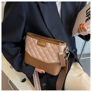 Detailaufnahme einer gesteppten Beuteltasche mit Goldkette und breitem Schultergurt