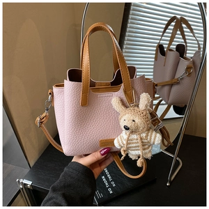 Detail of pink pebbled leather handbag with brown handles and a cute plush rabbit charm