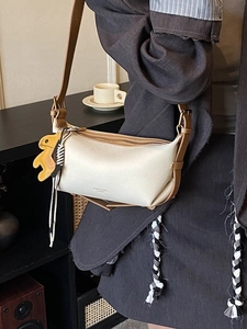 Sac bandoulière chic crème et marron avec breloque animal jaune porté par un mannequin