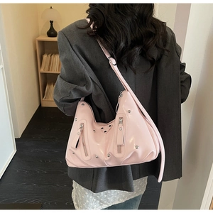 Detail of pink patent leather hobo bag with silver studs and buckles on model