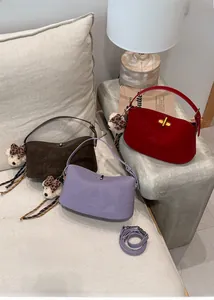 Detail of small crossbody bags in brown, purple, and red with teddy bear charms