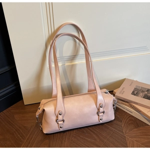 Detailaufnahme der rosa Zylindertasche mit Nieten und Metallreißverschluss an einer Holztür