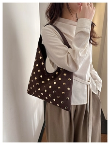 Detailed view of the dark brown suede shoulder bag with gold metal rivet decorations