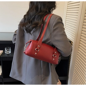 Detail der roten Leder-Schultertasche mit silbernen Metallringen und Nietendekor