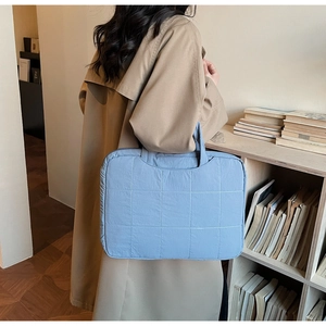 Quilted light blue laptop bag with top handles shown with a stylish trench coat