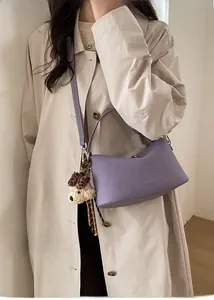 Detail of lavender purple leather crossbody bag with cute teddy dog plush charm accessory