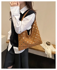 Close-up of brown suede tote bag featuring vintage gold rivets and shoulder strap