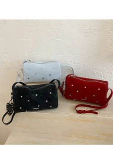 Vue détaillée de trois sacs cloutés en noir, rouge et bleu sur une surface en pierre