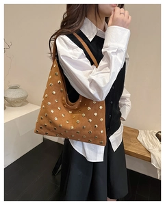 Detail view of brown suede hobo bag with vintage gold rivets shown on model shoulder