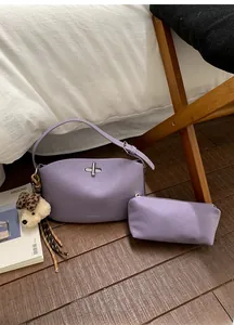 Detail of purple matte leather crossbody bag set with silver turn-lock and plush charm