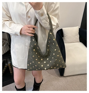 Detail of olive green suede shoulder bag featuring decorative gold metal rivets
