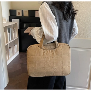 Detailed close-up of khaki quilted laptop bag with reinforced handles in a modern office