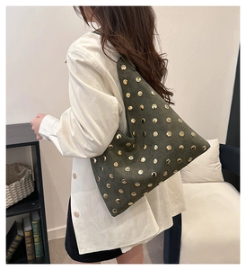 Detail of vintage olive green suede tote bag with circular gold rivet studs on shoulder