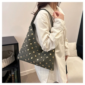 Close-up of moss green suede hobo bag with vintage gold rivets in a home setting