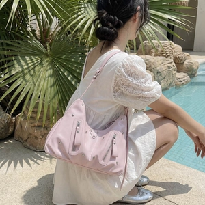 Pink studded leather hobo bag for women in a sunny outdoor resort pool setting