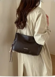Detail view of brown leather bag with white stitching and decorative baseball charm