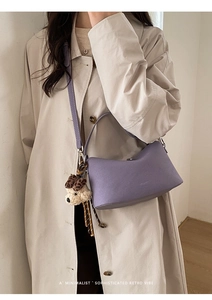 Fashionable purple faux leather hobo bag with a cute plush puppy charm worn on a trench coat