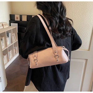 Rosa Zylinder-Achseltasche aus Leder am Model in gemütlicher Bibliotheksatmosphäre