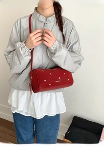 Détail du sac cylindrique rouge avec rivets étoiles argentés et fine bandoulière