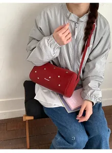 Détail du sac bandoulière cylindrique rouge avec clous étoiles et bandoulière en cuir