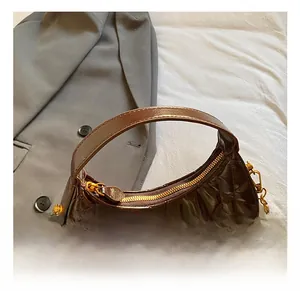 Detailed macro view of dark brown quilted crescent bag with gold chain and polished finish