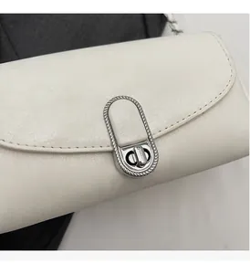 Dettaglio della borsa in pelle bianca con chiusura a scatto argento e bordo intrecciato