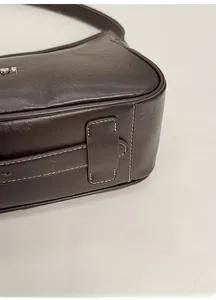 Detail of dark brown leather handbag with contrast stitching and heart metal logo