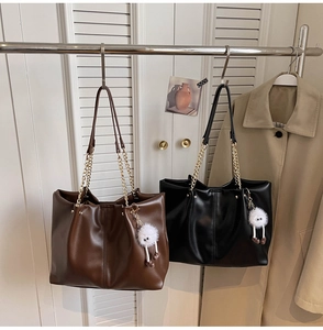 Detail of soft PU leather tote bags in brown and black with chain straps and plush charms