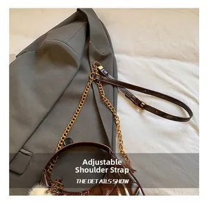 Detail view of dark brown quilted crescent bag with gold chain and plush charm