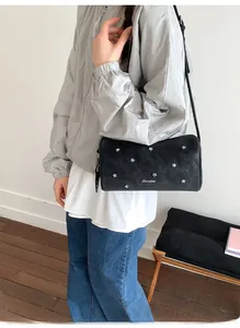 Détail du sac cylindrique noir avec rivets en étoile argentés et texture en cuir lisse