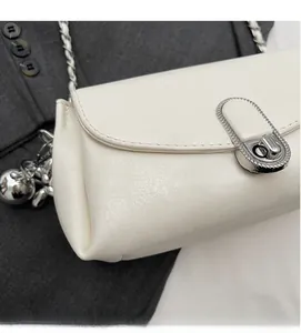 Dettaglio della borsa a tracolla in pelle PU bianco crema con chiusura a scatto ovale argento