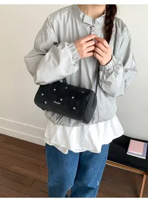 Détail du sac cylindrique noir avec clous en forme d'étoile argentés et logo imprimé