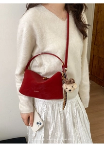 Deep red leather handbag featuring gold hardware and a leopard print bear charm accessory