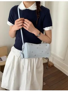 Détail des rivets en forme d'étoile sur un sac Boston en cuir bleu clair avec bandoulière