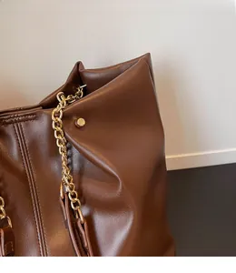 Close-up of brown leather tote bag showing soft texture and gold chain strap detail