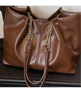 Detail view of the smooth long strap and gold chain on this brown large tote bag