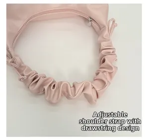 Detail of pink crossbody bag with pleated strap and adjustable drawstring design