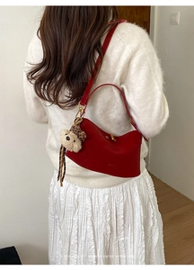 Detail of red leather shoulder bag with gold hardware and cute teddy bear charm accessory