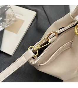 Détails de la texture du cuir crème et de la quincaillerie dorée du sac seau