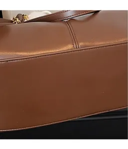 Close-up of brown leather tote bag bottom with detailed stitching and gold hardware