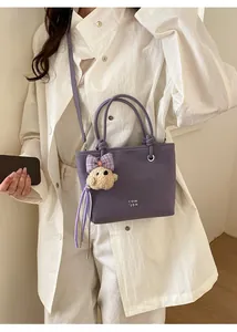 Detail of purple bucket bag with fine texture, printed logo and cute dog charm pendant