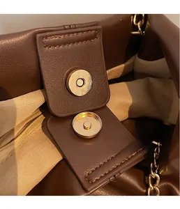Detailed close-up of dark brown leather texture with golden magnetic snap closure