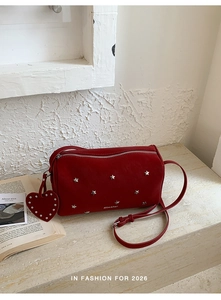 Détail du sac polochon rouge avec clous en forme d'étoile et pendentif en cœur