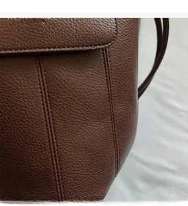Close-up of brown litchi grain leather flap with precision stitching and embossed text