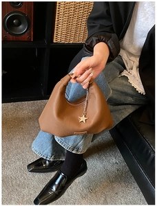 Dettaglio borsa hobo marrone motivo litchi con ciondolo a stella e placca logo