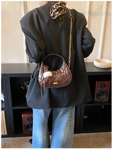 Quilted half-moon bag in dark brown glossy finish with gold chain and plush keychain