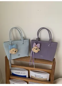 Close-up of stylish bucket bags featuring unique knotted handles and cute bear charms