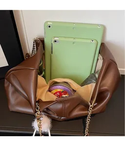 Macro view of large brown tote bag showing spacious interior with tablet and metal chain