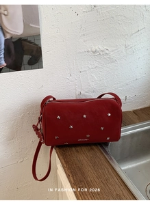 Détail du sac polochon rouge avec rivets en forme d'étoile et fermeture éclair