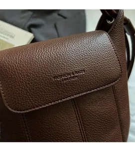 Close-up of brown litchi pattern leather texture and Fashion logo on the shoulder bag